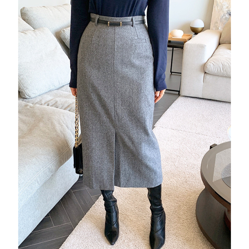 グレーのヘリンボーン柄タイトスカート。片脚を前に置いた斜め向きの姿。前側のスリットとタイトな裾