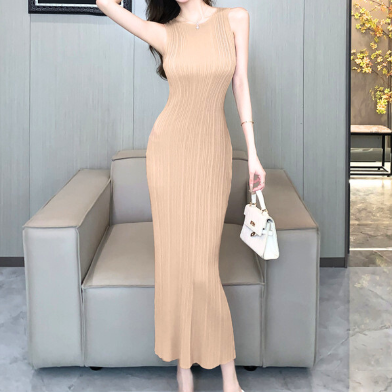 ベージュのバックスリット入りリブニットワンピースで室内に立つ女性