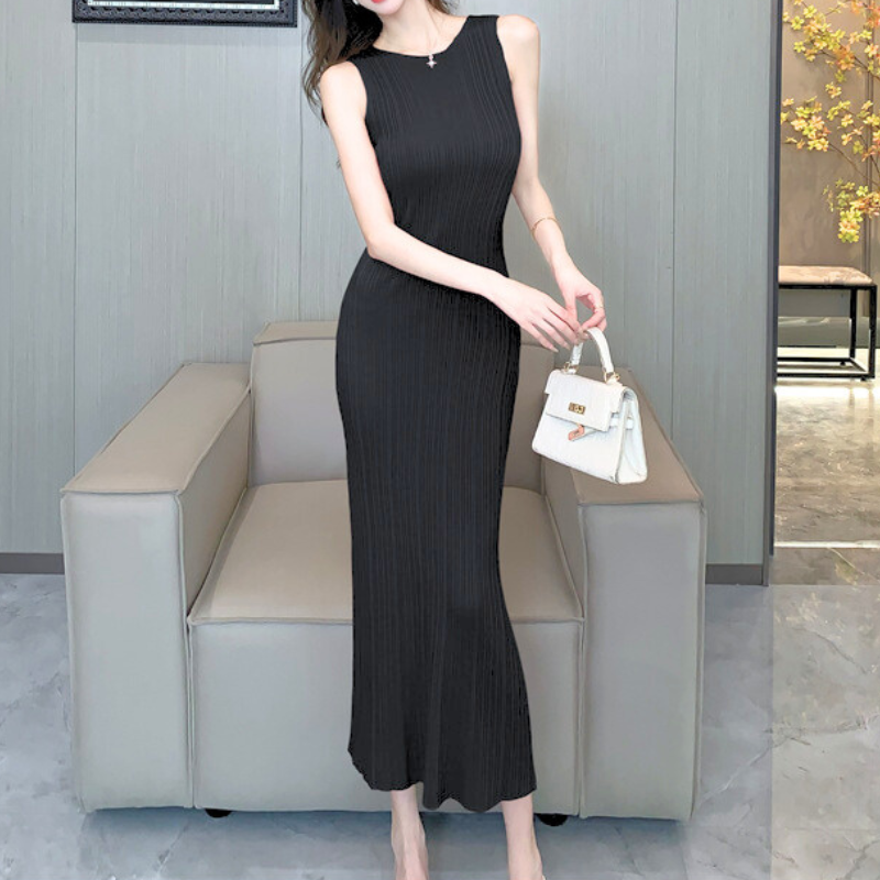 ブラックのリブニットワンピースでソファ前に立つ女性