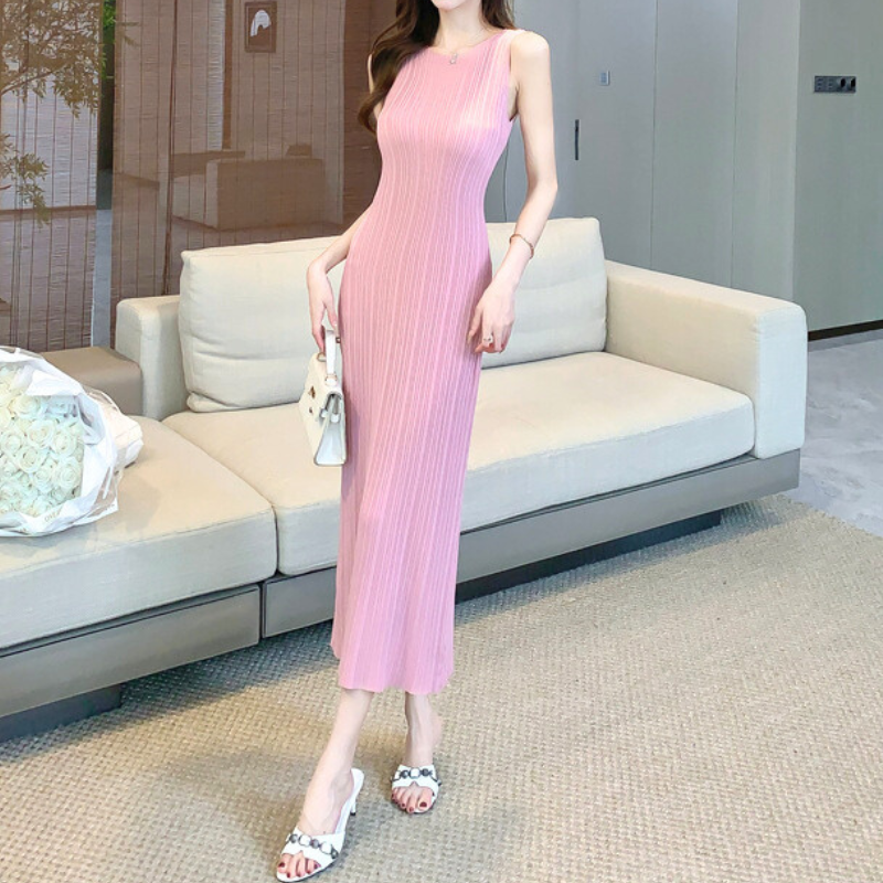 ピンクのリブニットワンピースでソファ横に立つ女性