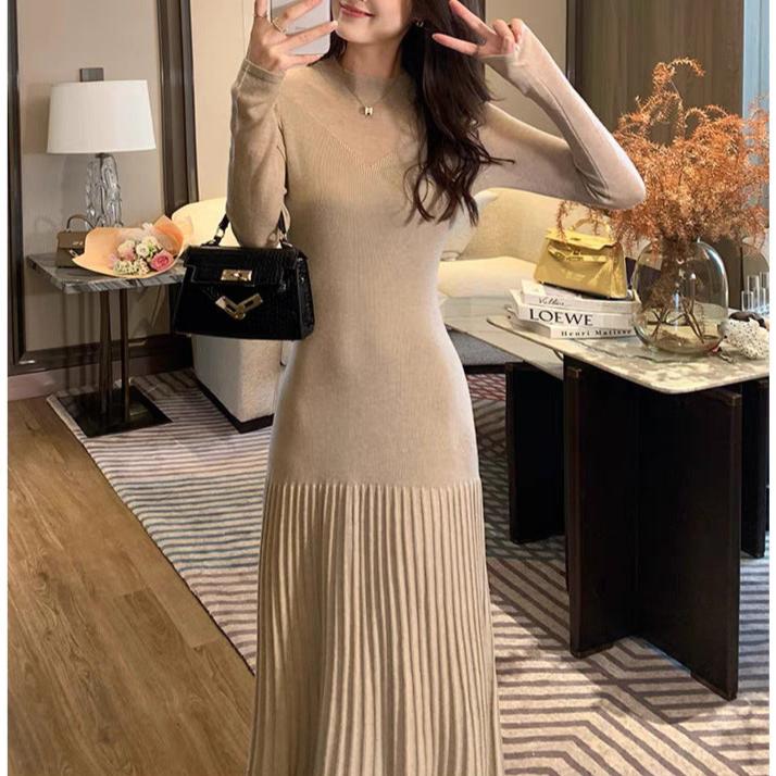 部屋の中で立つ女性(ベージュのシアースリーブワンピース)