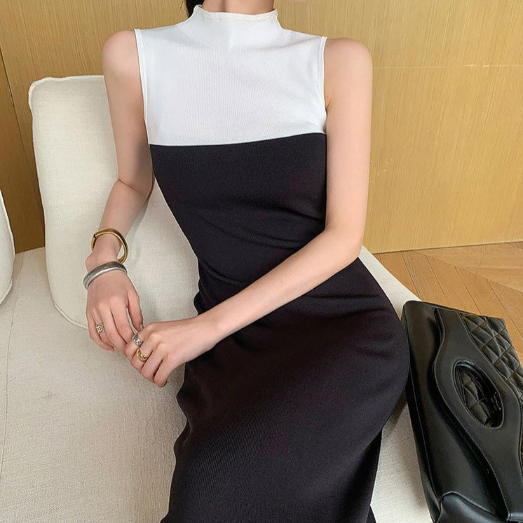 椅子に座りながら、バイカラーハイネックニットワンピースの上品なシルエットをアピールする女性