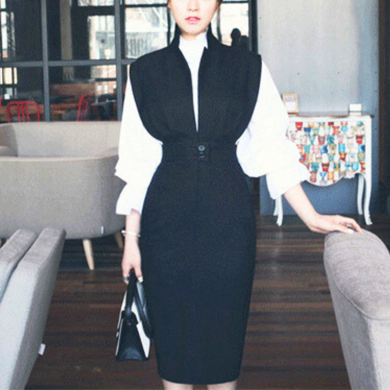 カフェチェアに手をかけて立つブラックジャンパースカートの前姿