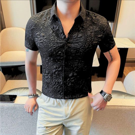 ブラックの艶感フラワー柄シャツを着た男性が立ってポーズをとっている様子