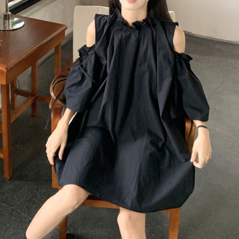 黒ワンピを着て椅子に腰掛けた大人カジュアルなスタイル。