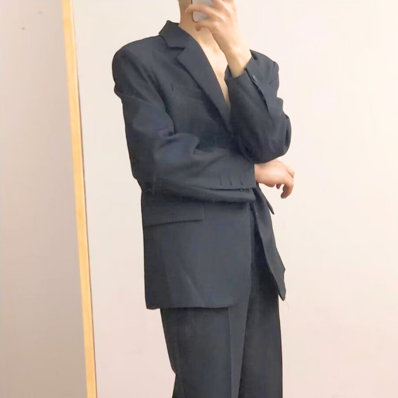 腕を組んだ姿勢でスタイリッシュに決まる黒スーツ