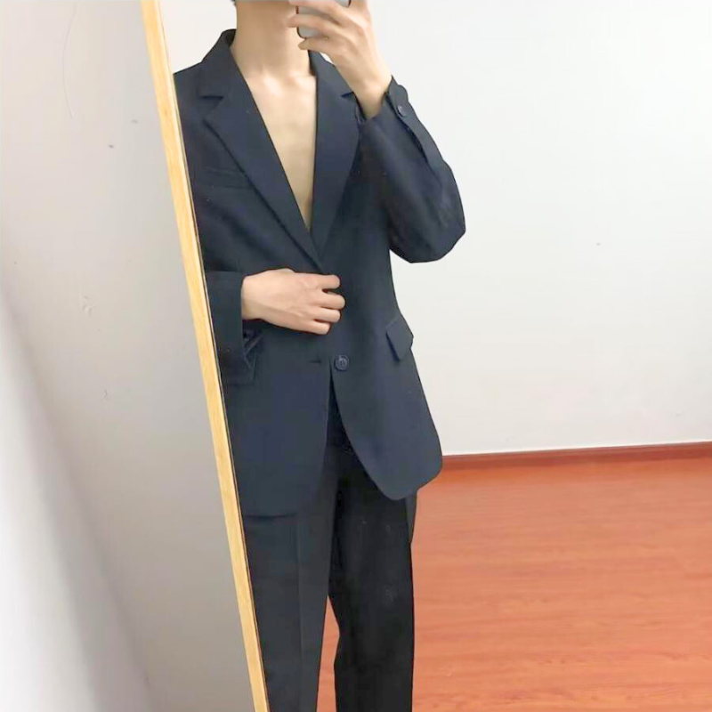 リラックス感のあるポーズで黒スーツを着用