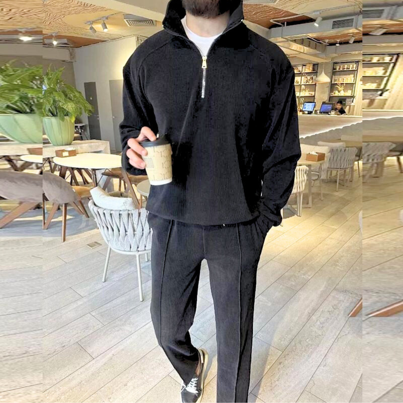 ブラックのハーフジップ上下セットアップを着た男性モデル(カフェ店内)