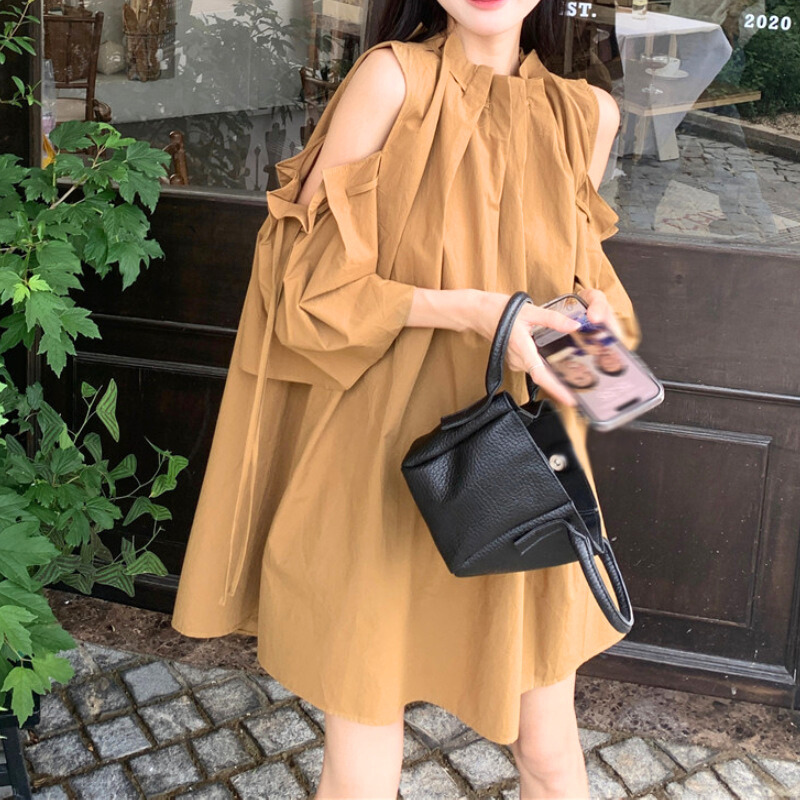 キャメルカラーのキャンディスリーブワンピを軽やかに着こなす女性。