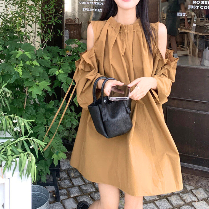 キャメルの肩あきギャザーワンピースを着た女性。カフェ前でナチュラルな印象に。