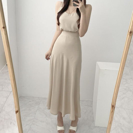 アイボリーのキャミソール&フレアスカートを上品に着こなす女性の全身ショット