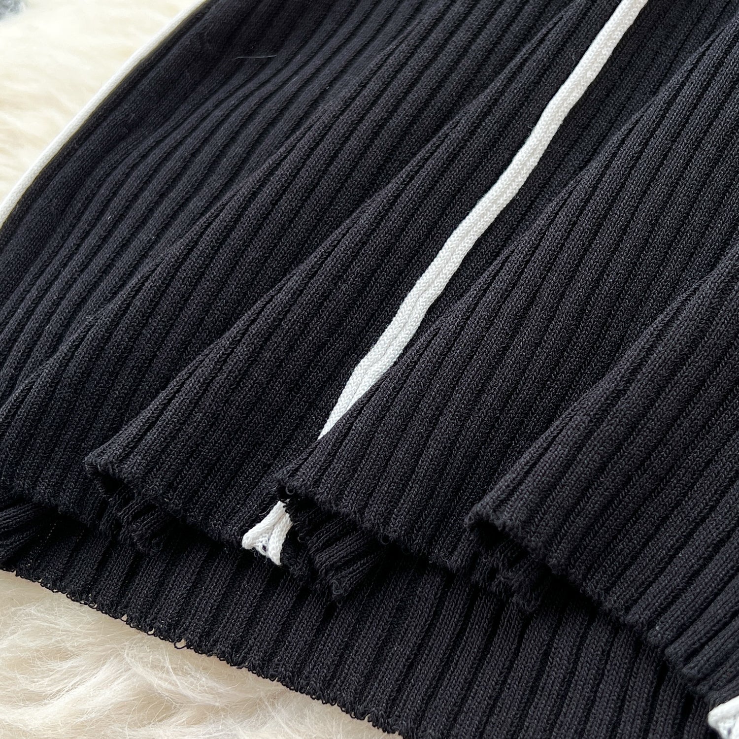 伸縮性のあるブラックのニット生地をクローズアップ。ホワイトラインがアクセントになったデザイン