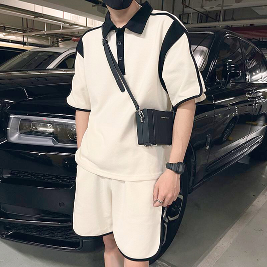 ブラックの車の前で配色ポロセットアップを着こなす男性の全身コーデ