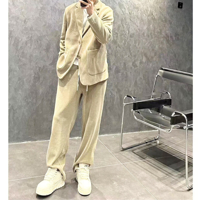 ベージュセットアップを立ったままポーズする男性