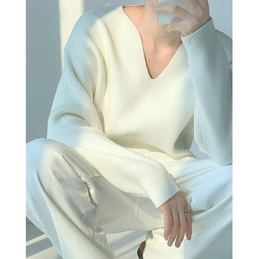 座りポーズでホワイトニットを着た男性、柔らかな空気感