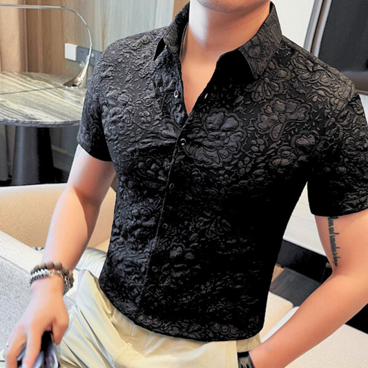 黒の艶感シャツを着た男性が室内で自然にポーズを決めている