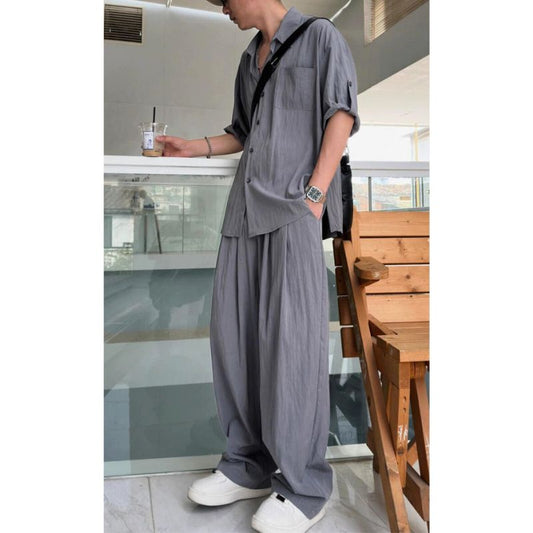 グレーカラーのセットアップを着こなす男性(カフェ風背景)