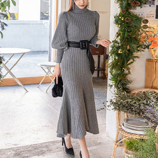 グレーのパフスリーブタートルネックマーメイドワンピース(ベルト付き)を着た女性