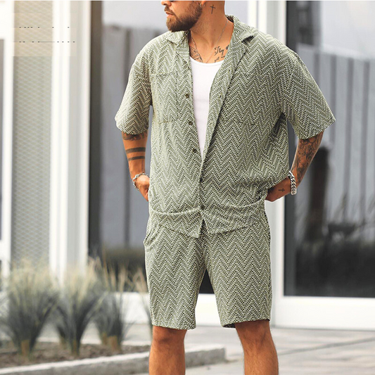 開襟シャツとハーフパンツのヘリンボーン柄セットアップを着た男性モデルが屋外でポーズを取る様子