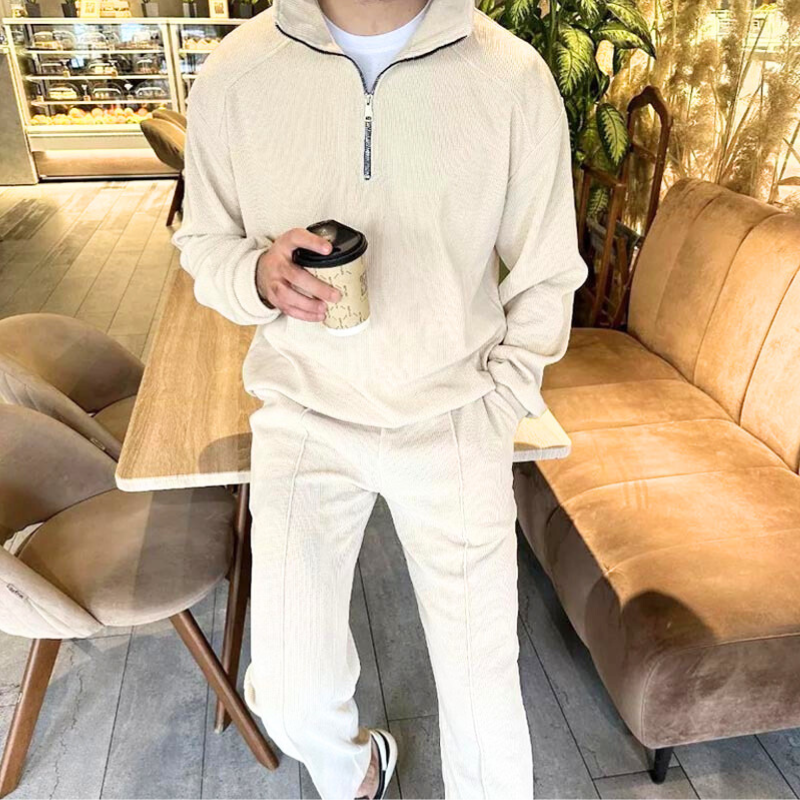 アイボリーのワッフルニットセットアップを着た男性モデル(店内シーン)