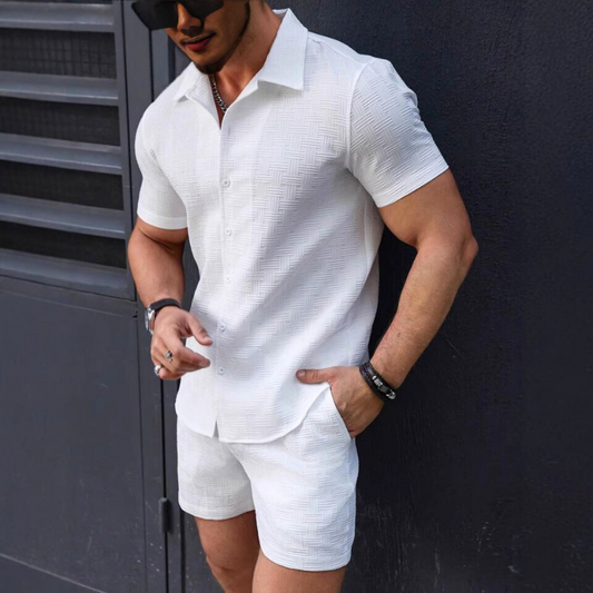 ホワイトの立体ジャカード半袖セットアップを着た男性が壁際に立つ様子