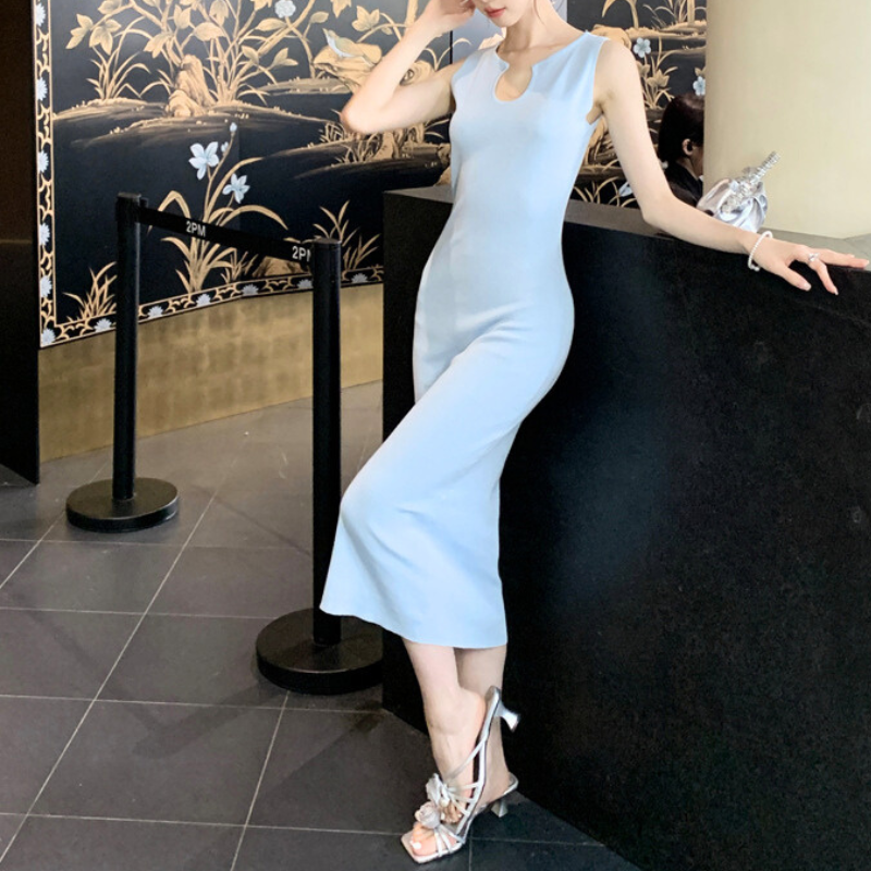 サックスブルーのワンピースで壁に腰掛ける女性