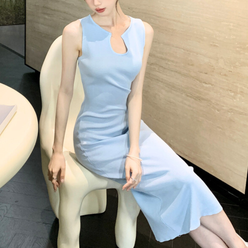 サックスブルーのキーネックノースリーブワンピースを着た女性が椅子に座っている姿