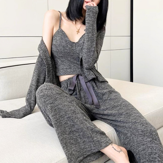 30代女性がベッドに座ってくつろぐニットカーデ付きルームウェア