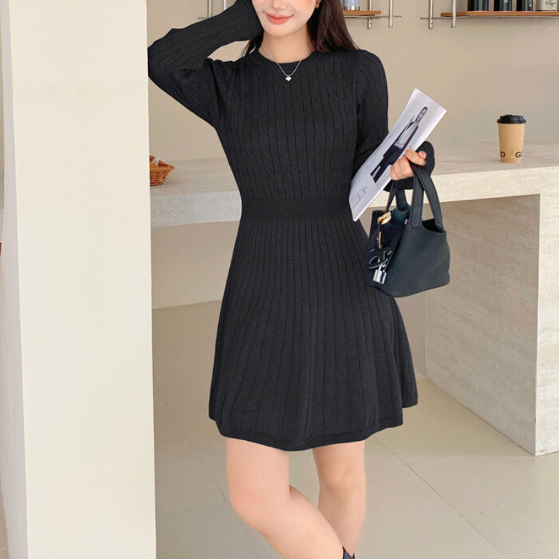 ニットワンピを着て微笑む女性。モノトーン小物が映えるコーディネート。