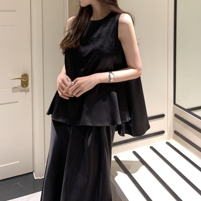 ブラックのノースリーブアシメトップス&フレアスカート サテンセットアップを正面から撮影し、シックな大人っぽさを強調
