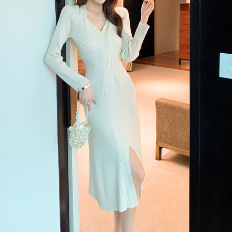 斜めから見たホワイトのニットワンピースで、Vネックカットアウトと程よい厚みのリブ素材をアピール