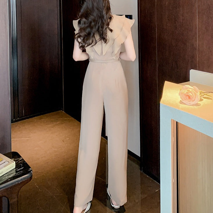 ベージュのパンツドレスを背面から撮影。フリルが程よく肩まわりをカバーし、後ろ姿も華やか