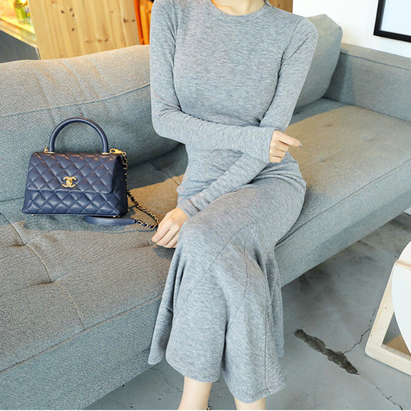 ソファに座り、タイトなウエストラインが際立つグレーのマーメイドワンピース