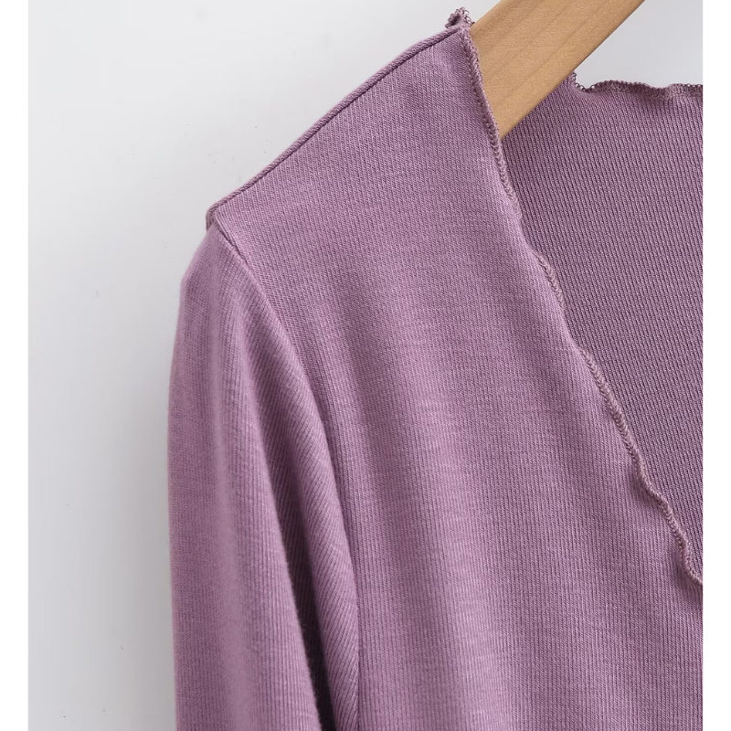 ショートカーディガンの襟元を接写し、軽やかな薄手カットソー素材と縁のフリルがわかる