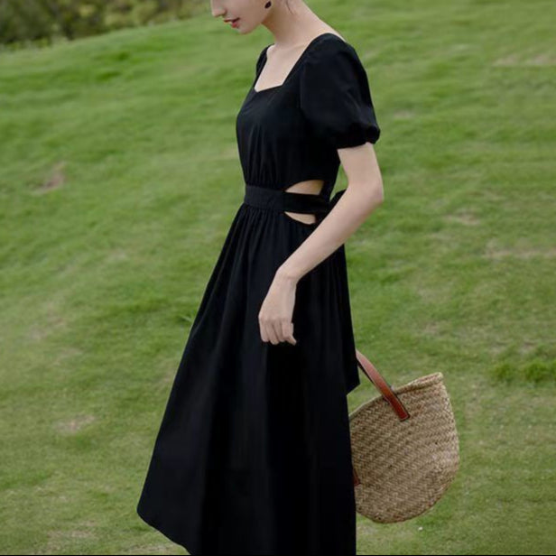 斜めから見たブラックワンピースで、ウエストの肌見せとフレアシルエットが大人かわいい印象を演出