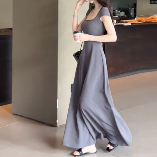 歩きながらグレーのフィット&フレアワンピースを着用する姿で、裾が揺れる女性らしいシルエット