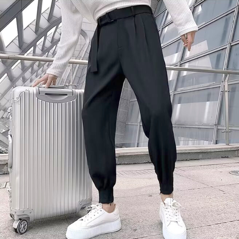 黒のタックパンツをスーツケースと合わせてラフに着こなす