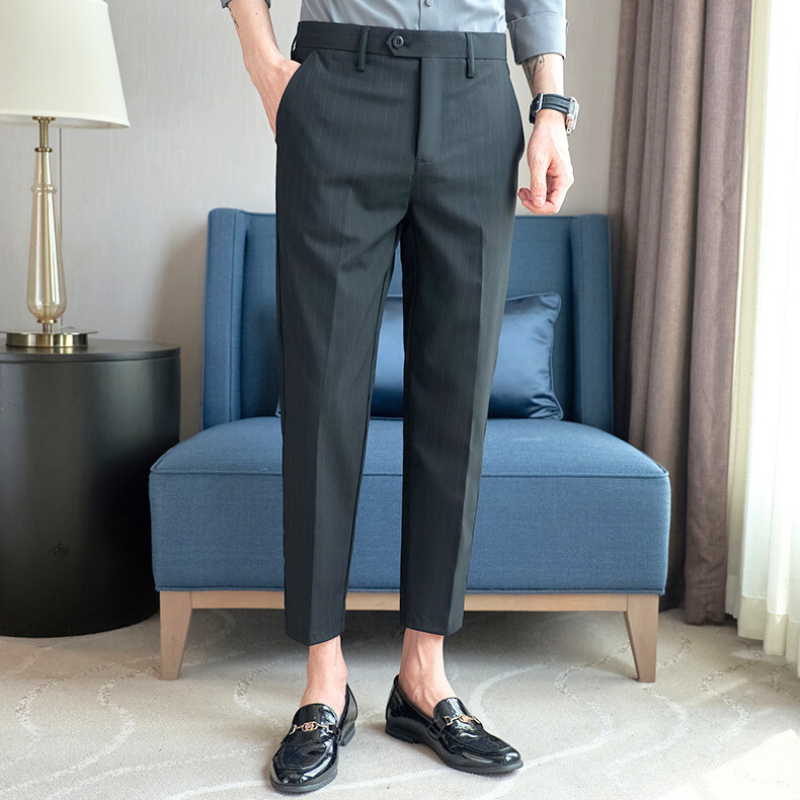 斜め立ちポーズで撮影された黒系ストライプパンツ。足元はローファーで引き締め。