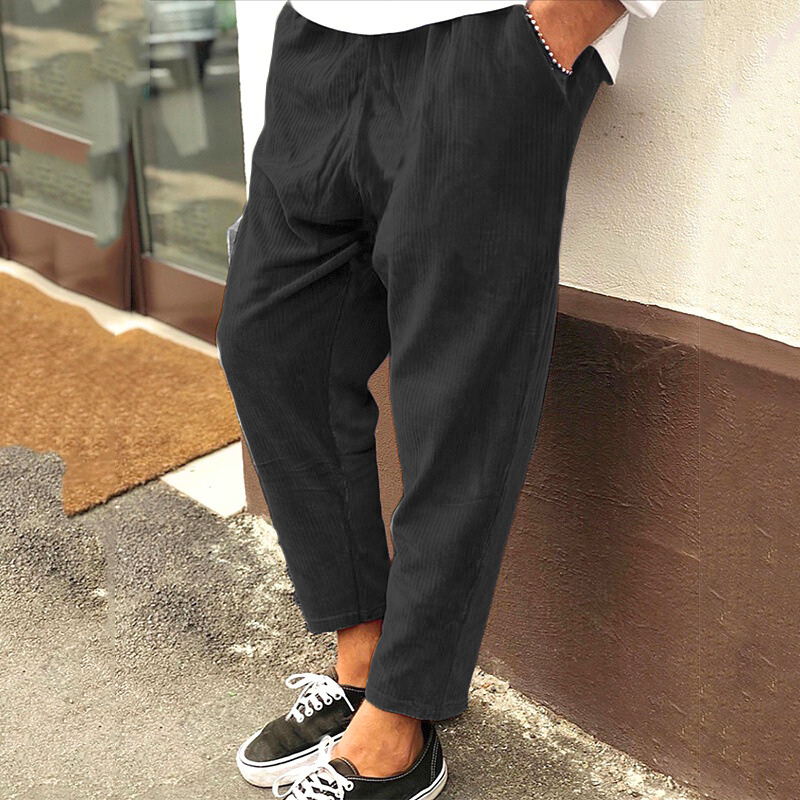 ブラックのコーデュロイパンツを穿いて立っている男性モデル