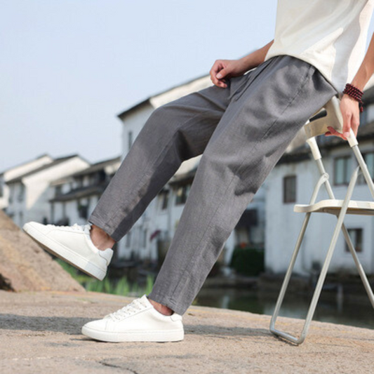 グレーのリネン混テーパードアンクルパンツを屋外で着用する男性モデル