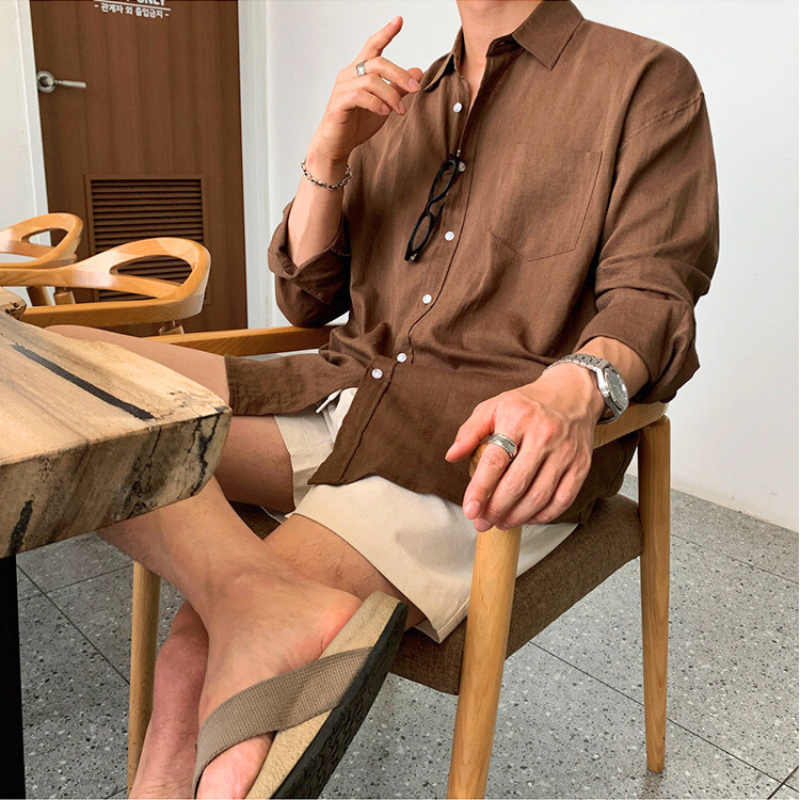 カフェでの着席シーン。ハーフパンツとブラウンシャツの上品な夏スタイル
