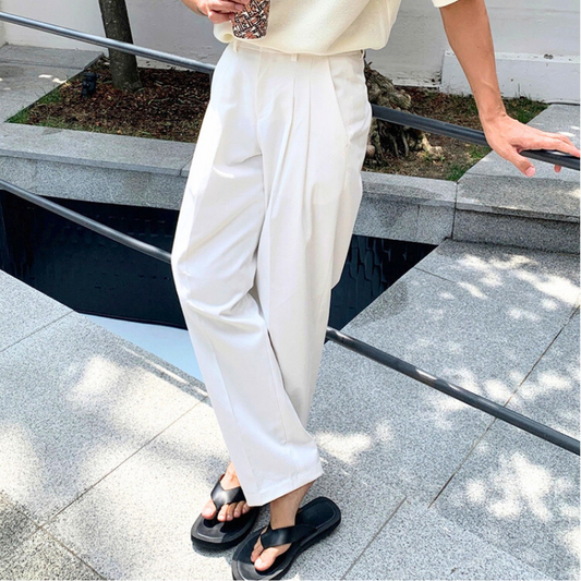 白のコットンストレートパンツを履いた男性が街角でポーズしている様子