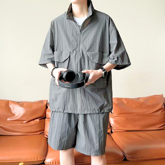 ナイロン風素材の半袖トップスとショーツのセットアップ(グレー)を着用した男性モデル