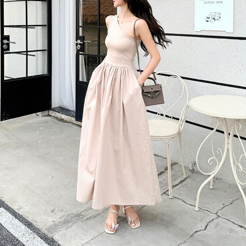 カフェテラスでベージュワンショルダーワンピを着る女性