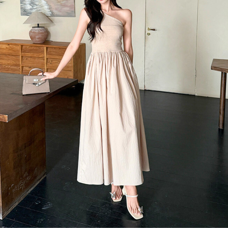 テーブルに手をついたポージングのベージュワンピ姿