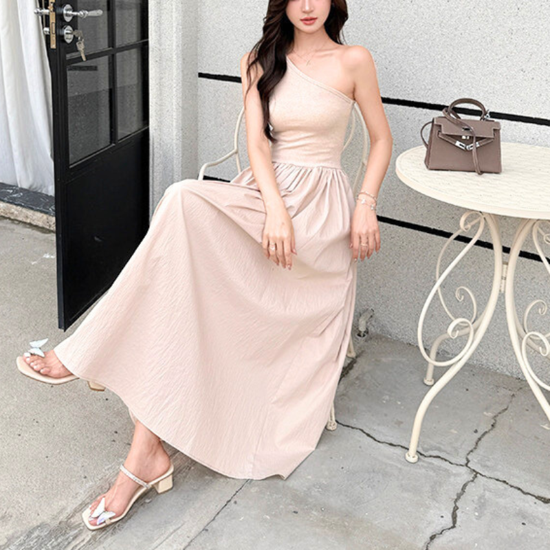 ピンクベージュのワンショルダーワンピでカフェのテラス席に座る女性