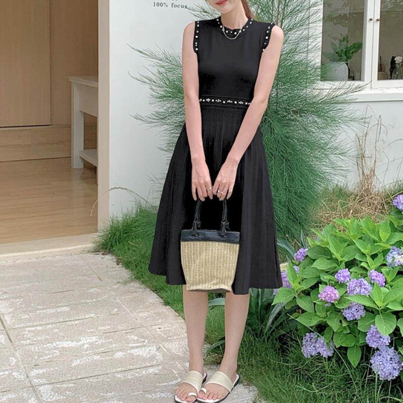 ブラックのノースリニットワンピを草花の前で立ち姿で撮影