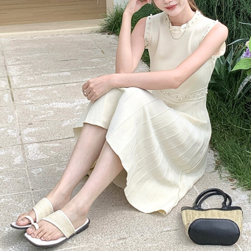 ホワイトニットワンピースを着て地面に座る自然体コーデ