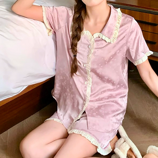 ベッド横でリラックスする女性と、淡い光沢のサテンパジャマ