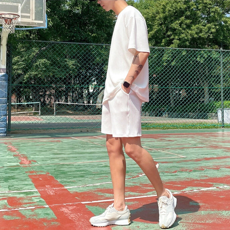 ショートパンツの白セットアップで横を向く男性(バスケットコート)